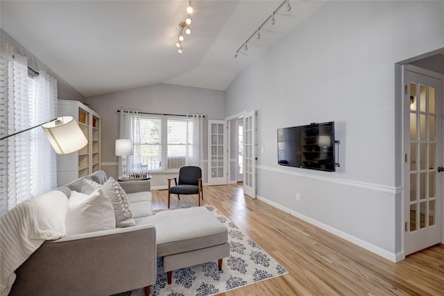living area with track lighting, baseboards, light wood-style floors, and vaulted ceiling