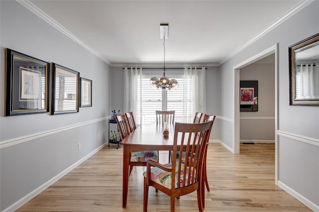 dining area featuring light wood finished floors, ornamental molding, and an inviting chandelier