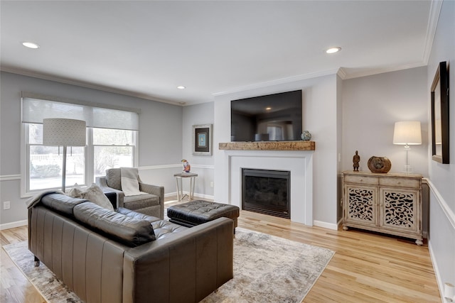 living room featuring baseboards, crown molding, wood finished floors, and a fireplace