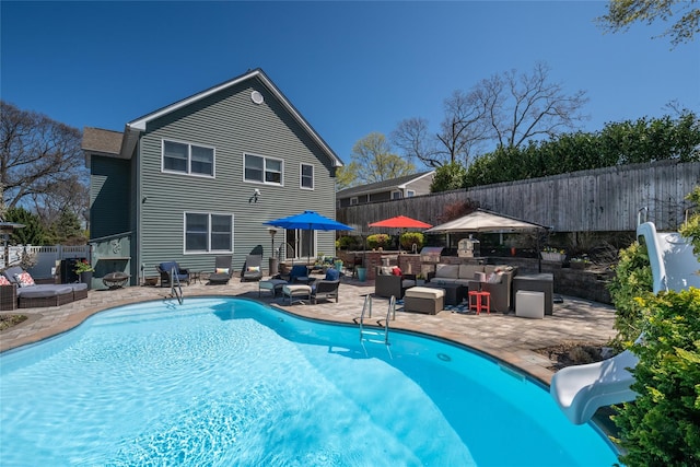 view of pool with a fenced in pool, a fenced backyard, a water slide, a patio area, and an outdoor living space