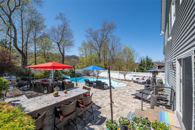 view of patio with area for grilling, exterior bar, a fenced in pool, and a fenced backyard
