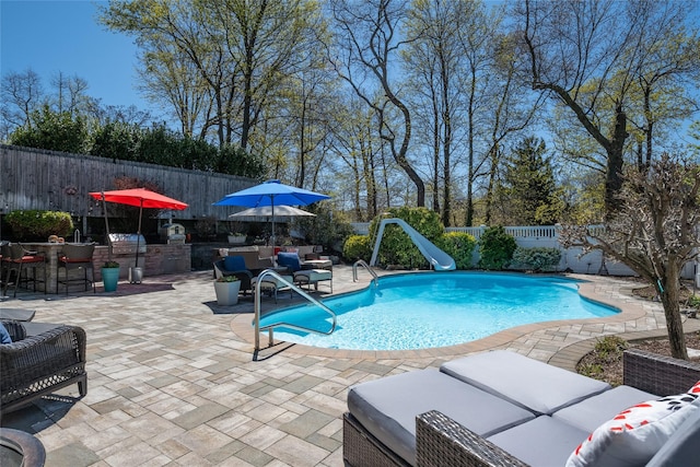 view of swimming pool with a fenced in pool, a fenced backyard, a water slide, a patio area, and an outdoor living space