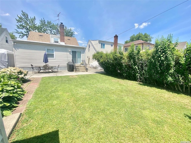 4947 166th St, Fresh Meadows, NY 11365 - rear view of house with a yard, entry steps, a patio area, and a chimney