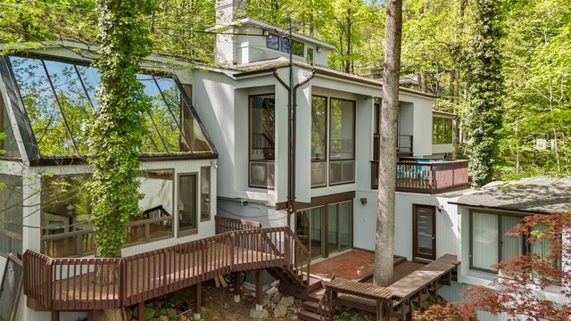 back of house with a chimney and a deck