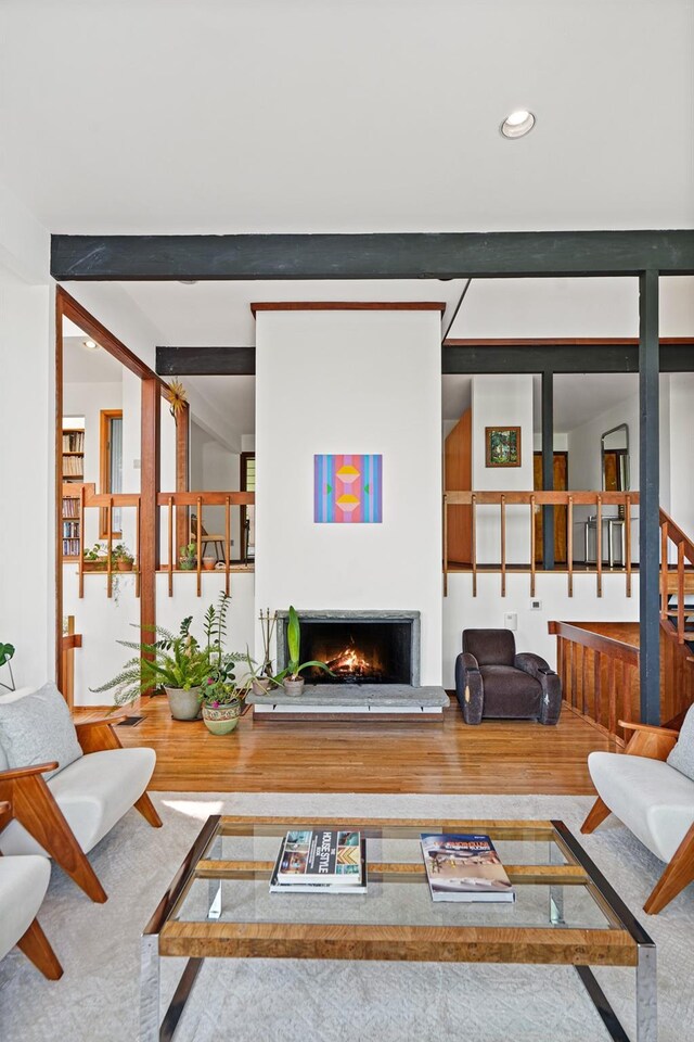 living room with recessed lighting, a warm lit fireplace, and wood finished floors