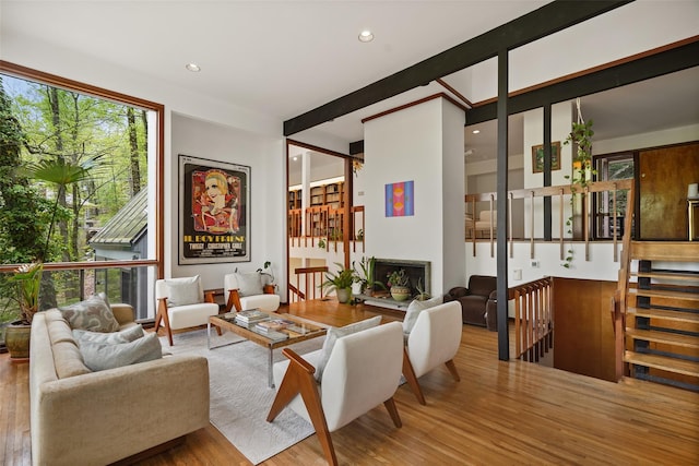 living area with a fireplace with raised hearth, recessed lighting, and wood finished floors