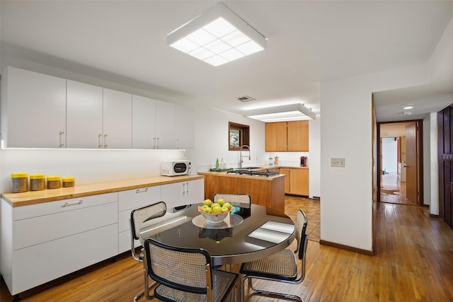 kitchen featuring visible vents, light countertops, light wood finished floors, and white microwave