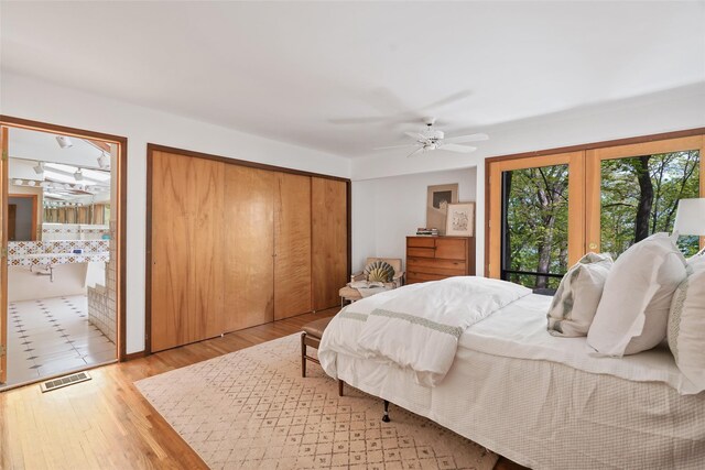 bedroom featuring connected bathroom, ceiling fan, visible vents, and wood finished floors