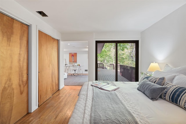 bedroom with light wood finished floors, multiple closets, and access to exterior