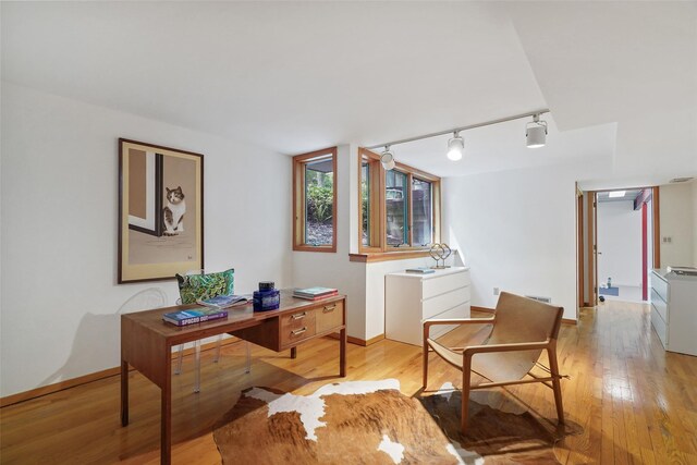 office with track lighting, baseboards, and light wood-type flooring