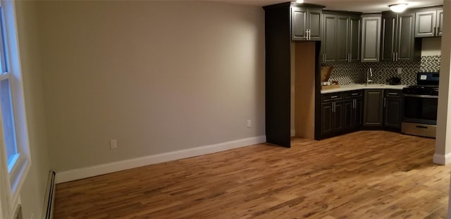 kitchen featuring baseboards, light wood-style flooring, a sink, and stainless steel range with gas cooktop