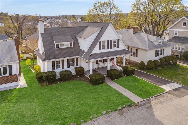 view of front facade featuring a shingled roof, a residential view, a porch, and a front lawn