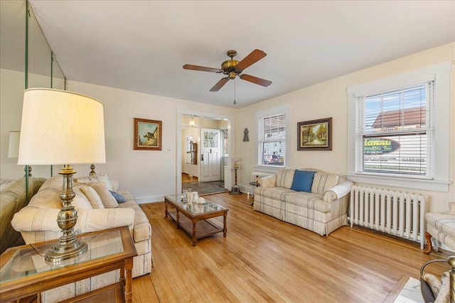 living room featuring light wood-style floors, radiator, baseboards, and a ceiling fan