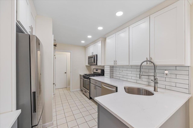 kitchen featuring light tile patterned floors, white cabinets, a sink, stainless steel appliances, and backsplash