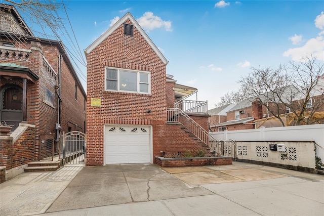 rear view of house featuring a garage, fence, brick siding, a gate, and driveway