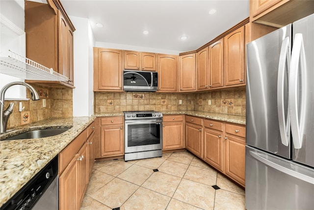 kitchen featuring a sink, appliances with stainless steel finishes, decorative backsplash, light tile patterned flooring, and light stone counters