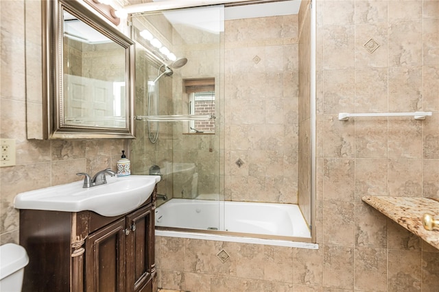 full bath with toilet, tiled shower / bath combo, tile walls, and vanity