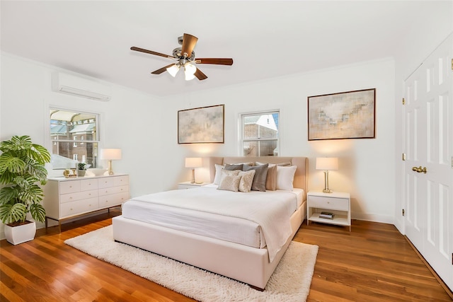 bedroom featuring a closet, baseboards, ornamental molding, a wall mounted AC, and wood finished floors