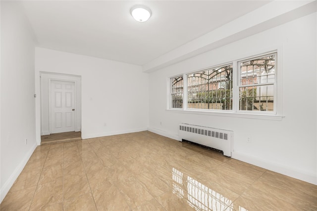 spare room featuring radiator and baseboards