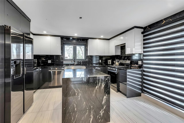 kitchen with modern cabinets, appliances with stainless steel finishes, decorative backsplash, and a sink