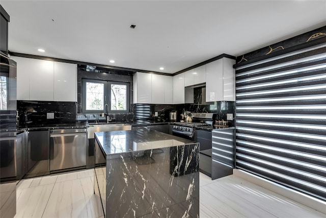 kitchen featuring dark stone counters, a sink, decorative backsplash, modern cabinets, and stainless steel appliances