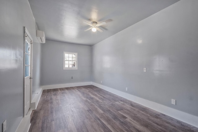 empty room featuring baseboards, dark wood-style floors, a wall unit AC, and ceiling fan