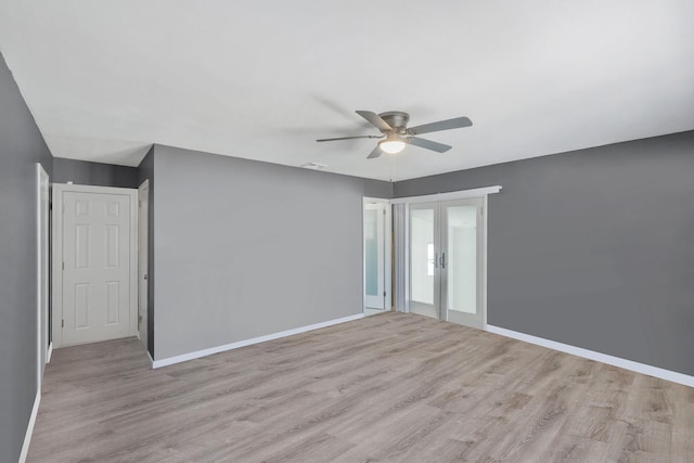 empty room featuring french doors, baseboards, a ceiling fan, and light wood-style flooring