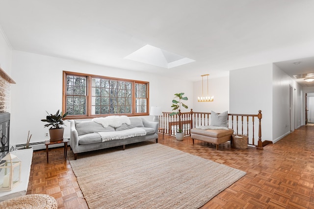 living area featuring a baseboard heating unit, a skylight, baseboards, and a chandelier