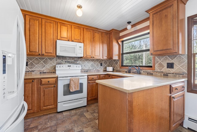 kitchen with a baseboard heating unit, brown cabinetry, white appliances, and a sink