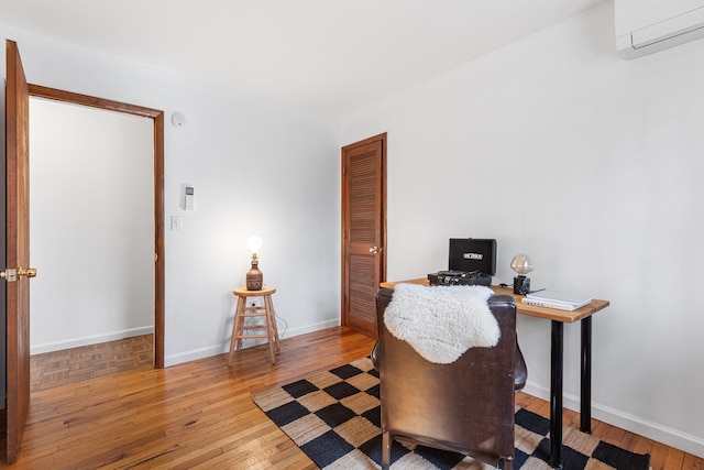 office featuring a wall mounted air conditioner, baseboards, and hardwood / wood-style floors