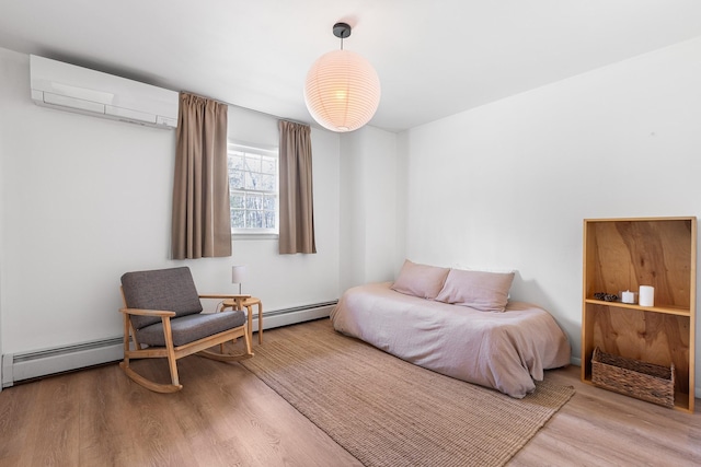 bedroom featuring a wall mounted air conditioner, wood finished floors, and baseboard heating