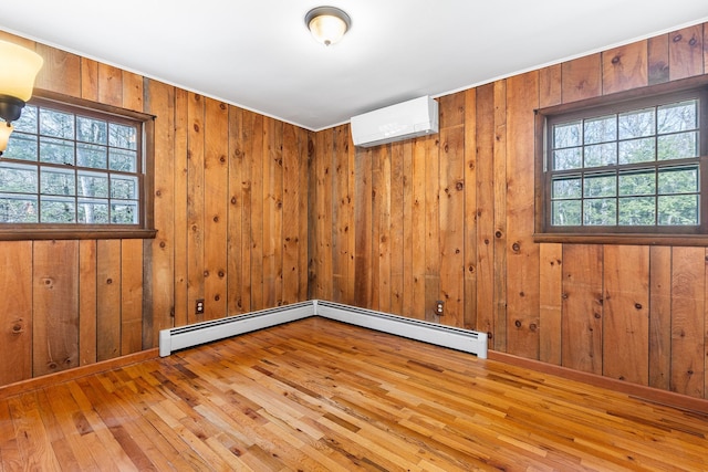 unfurnished room featuring wooden walls, a wall mounted air conditioner, a wealth of natural light, and hardwood / wood-style floors