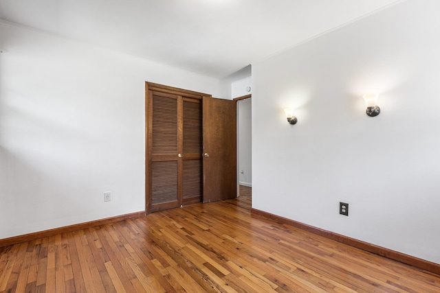 unfurnished bedroom featuring hardwood / wood-style floors, a closet, and baseboards