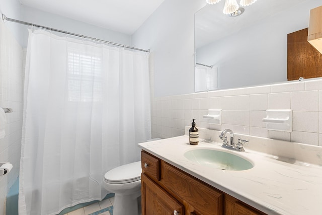 full bath with a wainscoted wall, toilet, tile walls, tile patterned flooring, and vanity