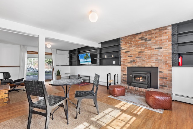 dining space with wood finished floors, a brick fireplace, and baseboard heating