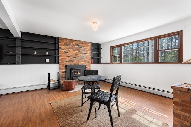 dining room with wood finished floors, built in features, and a baseboard radiator