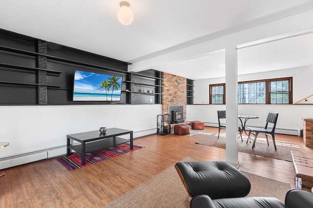 living room with a baseboard heating unit, wood finished floors, and built in shelves