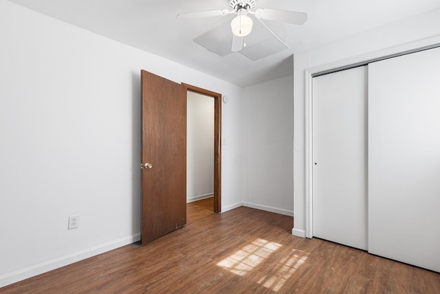 unfurnished bedroom with ceiling fan, baseboards, wood finished floors, and a closet