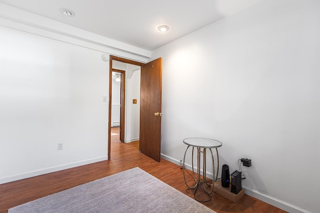 empty room featuring baseboards, baseboard heating, and wood finished floors