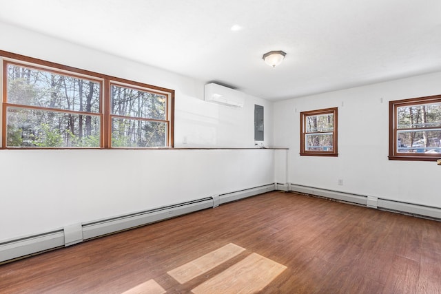 spare room with an AC wall unit, a wealth of natural light, wood finished floors, and electric panel
