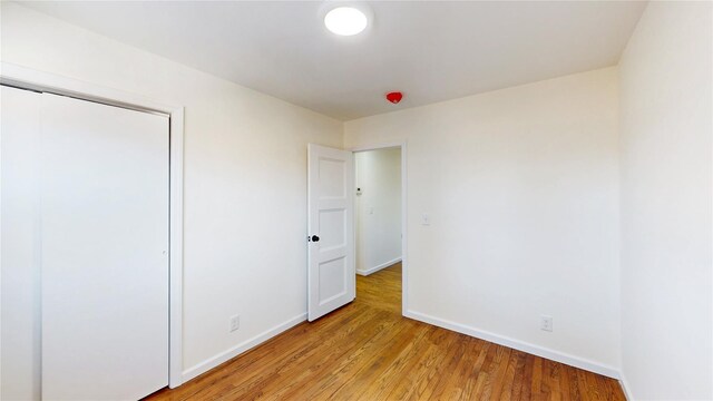 unfurnished bedroom featuring baseboards, a closet, and light wood-style flooring