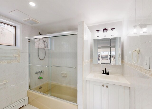 full bath featuring vanity, tile walls, bath / shower combo with glass door, and a baseboard radiator