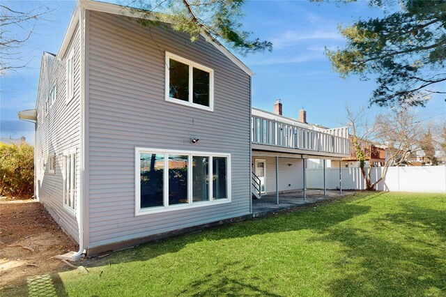 rear view of house featuring fence, a yard, and a deck