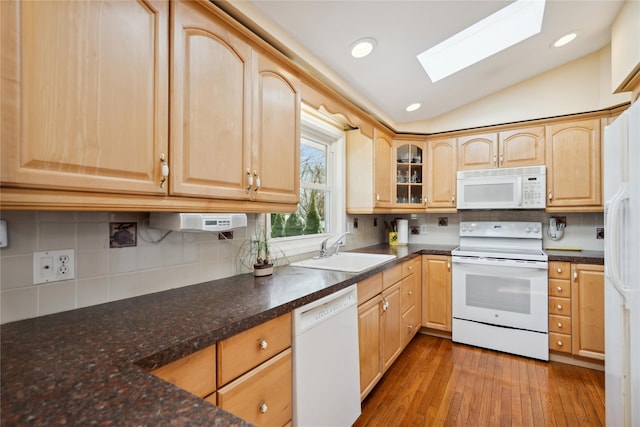 kitchen featuring a sink, lofted ceiling with skylight, light brown cabinets, and white appliances