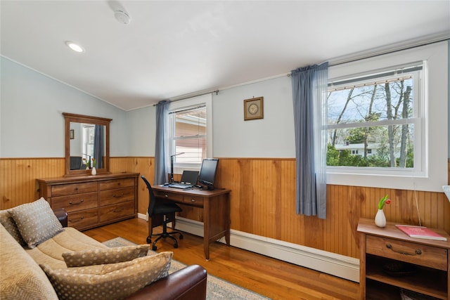 office area featuring a wainscoted wall, vaulted ceiling, wood walls, and a baseboard heating unit