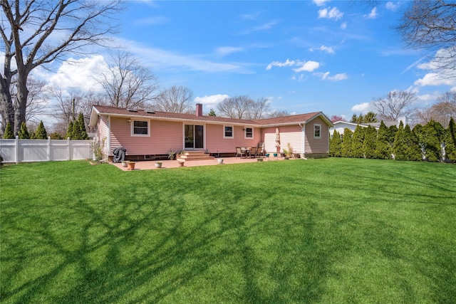 rear view of house with a patio, fence, a yard, and a chimney