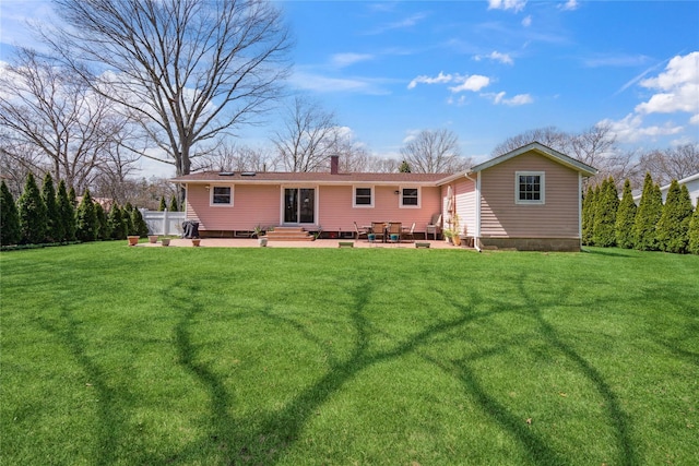 rear view of house featuring a lawn, a patio, and a chimney