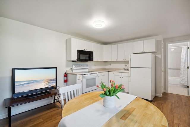 kitchen with a sink, white appliances, light countertops, white cabinetry, and dark wood-type flooring