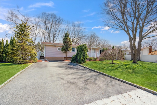 single story home with a front lawn, fence, and driveway