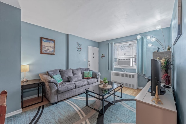 living area with cooling unit, radiator, wood finished floors, and baseboards